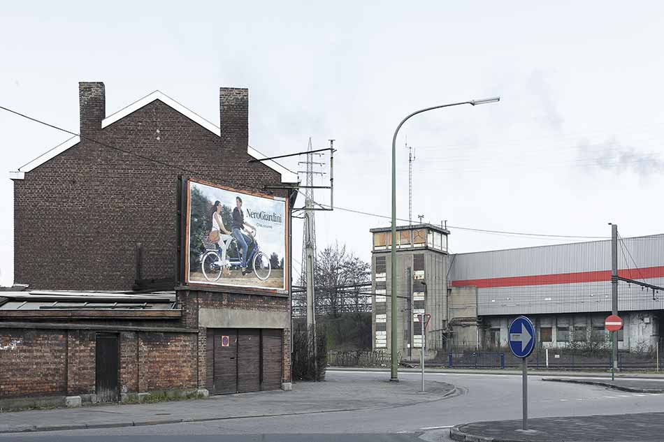 A view on an abandoned industrial area with a billboard advertising for NeroGiardini Chaussures