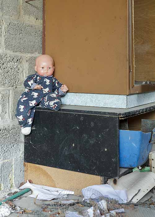A doll on the mantelpiece in a house being demolished