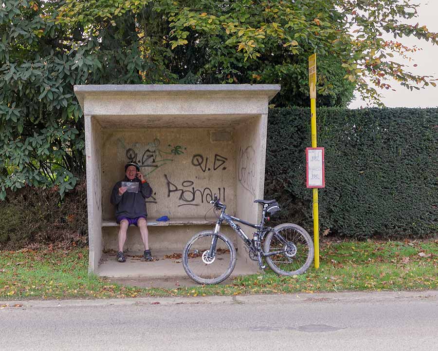 A cyclist talking on the phone in a bus shelter