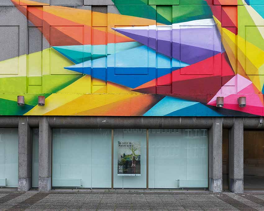 A brightly colored mural and a poster reading "Un siècle de peinture Belge"