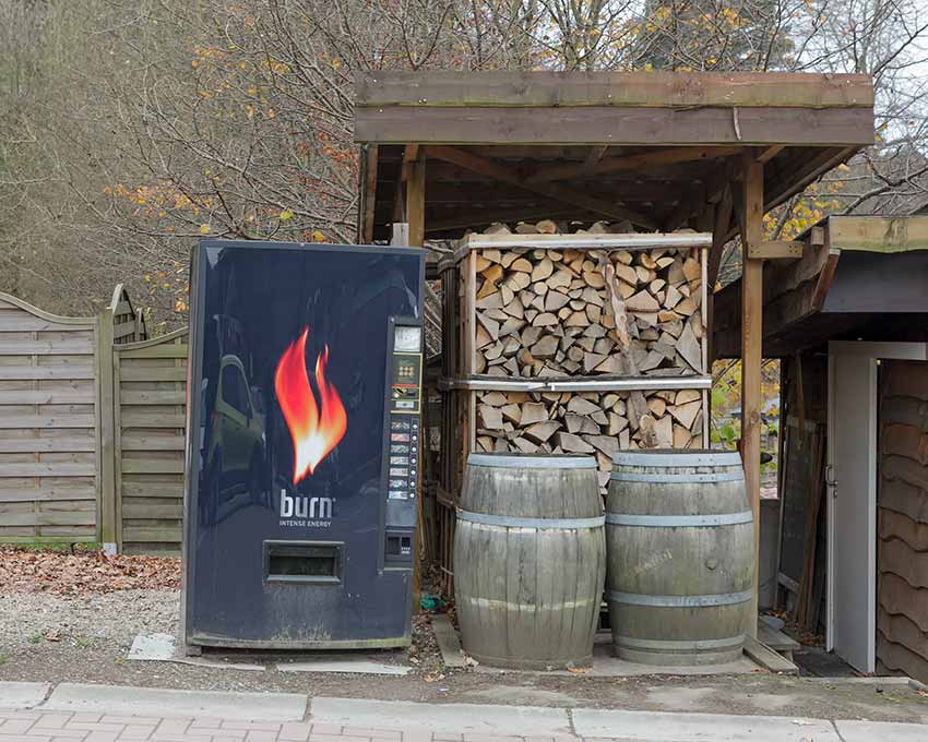 A pile of firewood next to a "Burn" energy drink vending machine