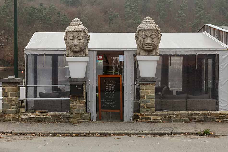 The entrance of a restaurant with two flower pots containing a Buddha head
