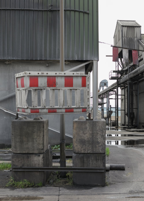 A red and white striped traffic barrier atop several concrete blocks