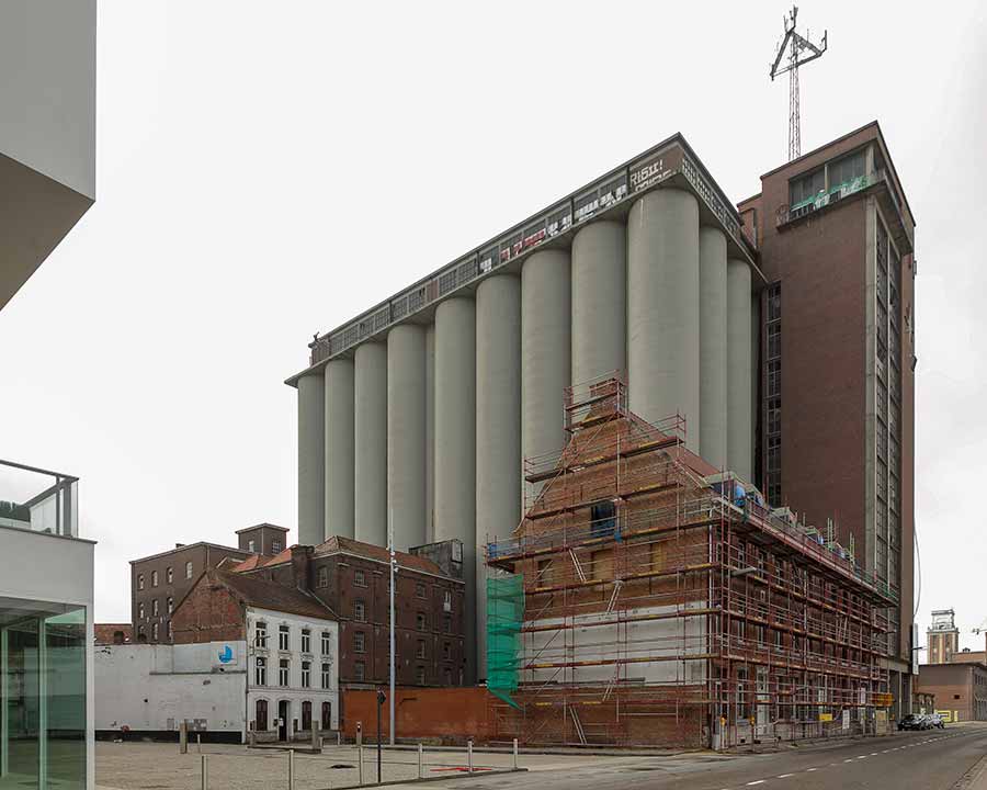 A historic building next to the silos of a feed factory