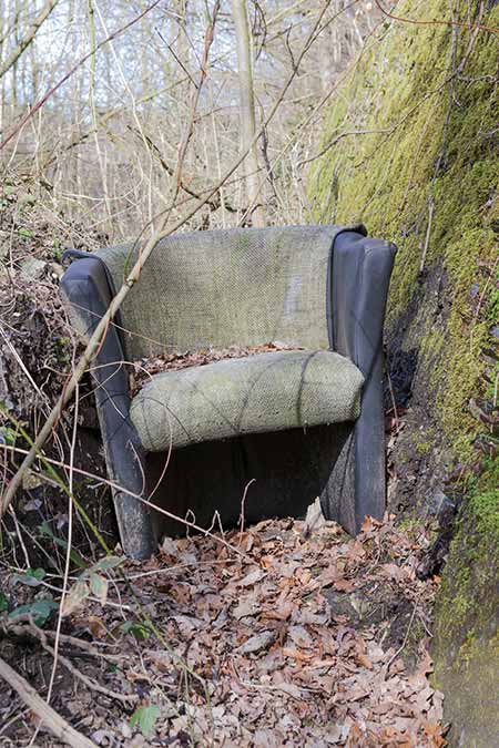 A discarded armchair among autumn leaves