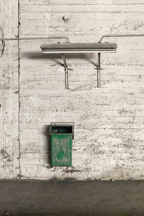A fluorescent lamp above a trash can in an abandoned factory