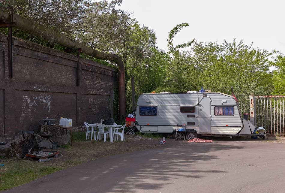 A caravan with camping gear next to an industrial pipeline