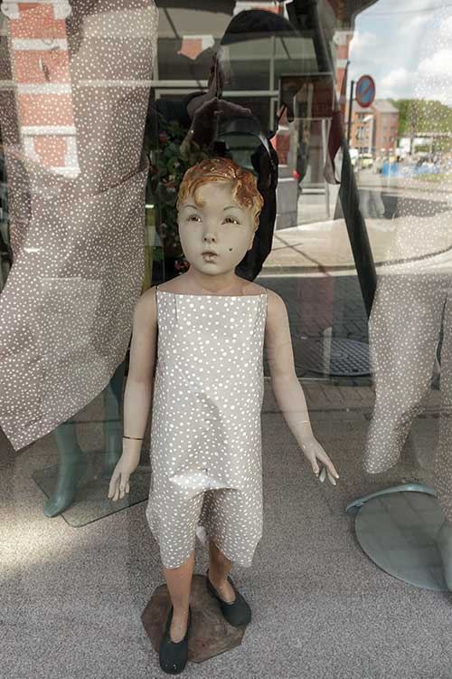 A shop window with a child's mannequin wrapped in paper