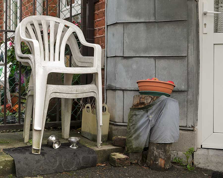 A plastic garden chair and shorts over a log